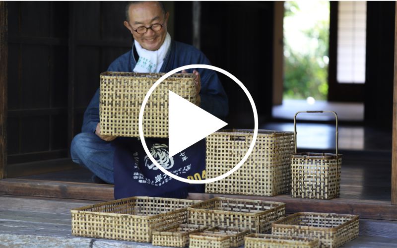Yoshihiro Yamagishi sitting next to a stack of tiger bamboo baskets