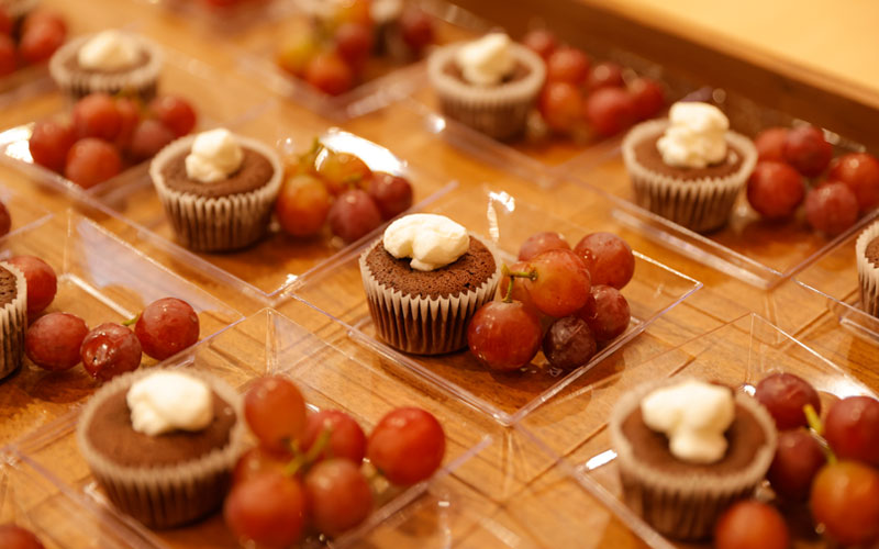 Chocolate cupcakes and grapes served on small, clear plates