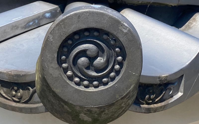 A closeup of a “kamon” (family crest) engraved on the corner of a roof tile.