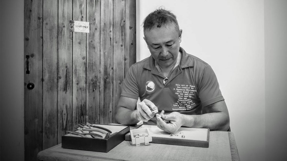 A person sitting at a table, working with pearls