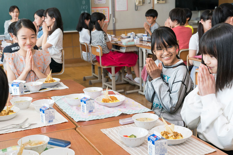 A group of students at their desks in the classroom, ready to begin eating their school lunches