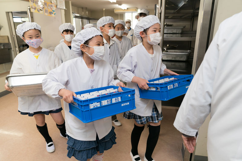 A group of students carrying their school lunches in the hallway