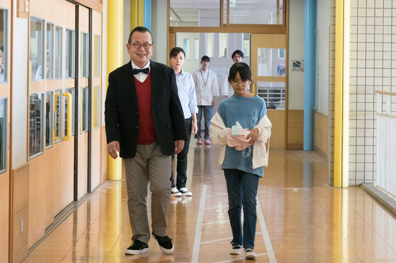 A student and a teacher walking in a school hallway