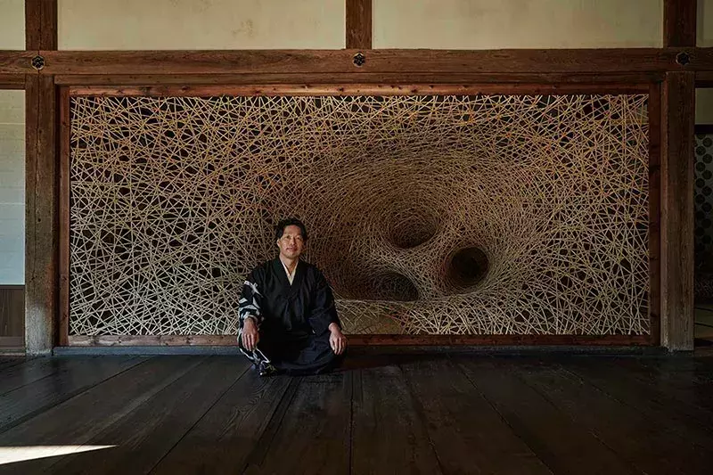 Chikuunsai IV sitting next to his work at Shokoji Temple