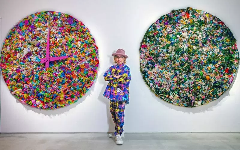 Artist Sebastian Masuda stands between his artworks, Colorful Rebellion