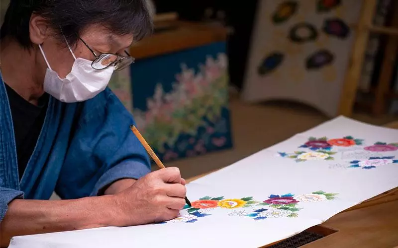 A man painting a variety color of flowers.