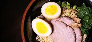 Top view of a bowl of ramen with noodles, broth, soft-boiled egg, and assorted toppings.